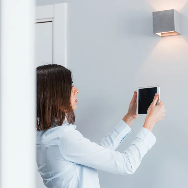 Une femme tenant une tablette devant un mur.